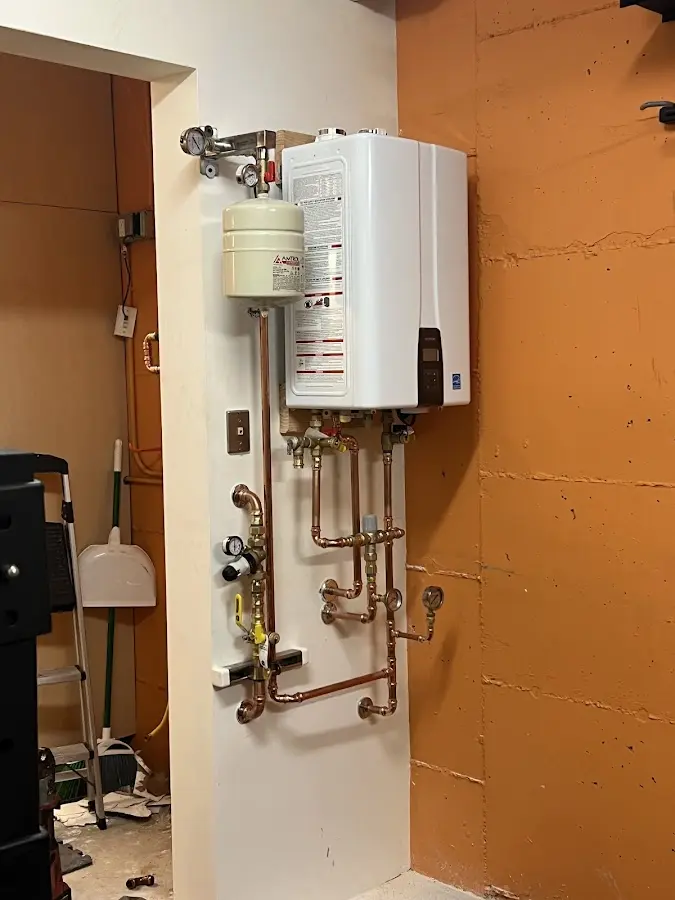 Plumbing technician inspecting water heater connections in Madison